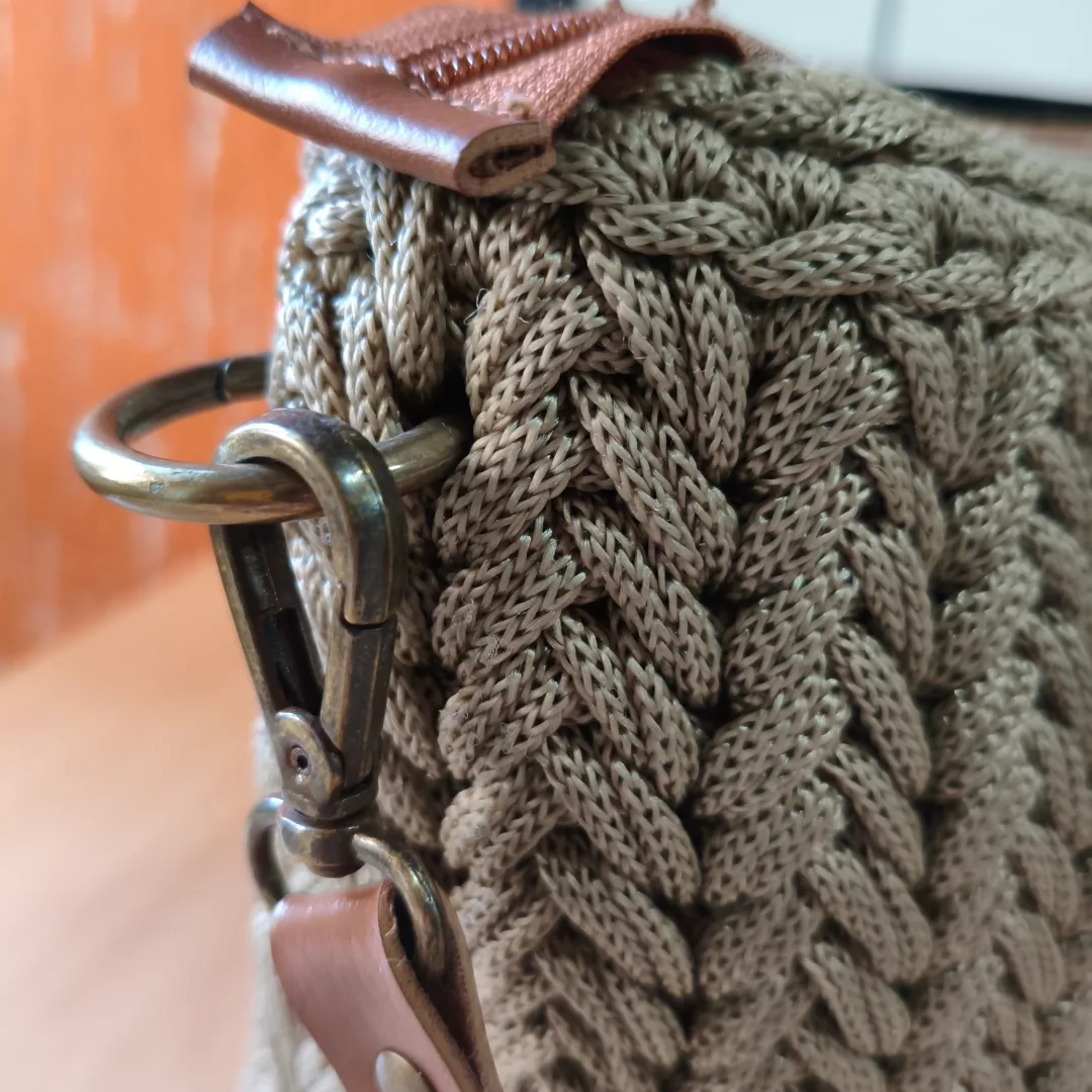 A Bolsa Essência foi criada para mulheres que acreditam que o verdadeiro luxo está na qualidade, no cuidado e na exclusividade do feito à mão.Confeccionada artesanalmente em fio náutico, seu trançado em relevo cria uma textura encantadora que valoriza cada ponto. A tonalidade creme traz leveza e sofisticação, combinando facilmente com diferentes estilos e ocasiões.  Seu acabamento impecável, o fechamento em zíper e a alça regulável unem beleza, praticidade e segurança para acompanhar você em todos os momentos. — foto 2