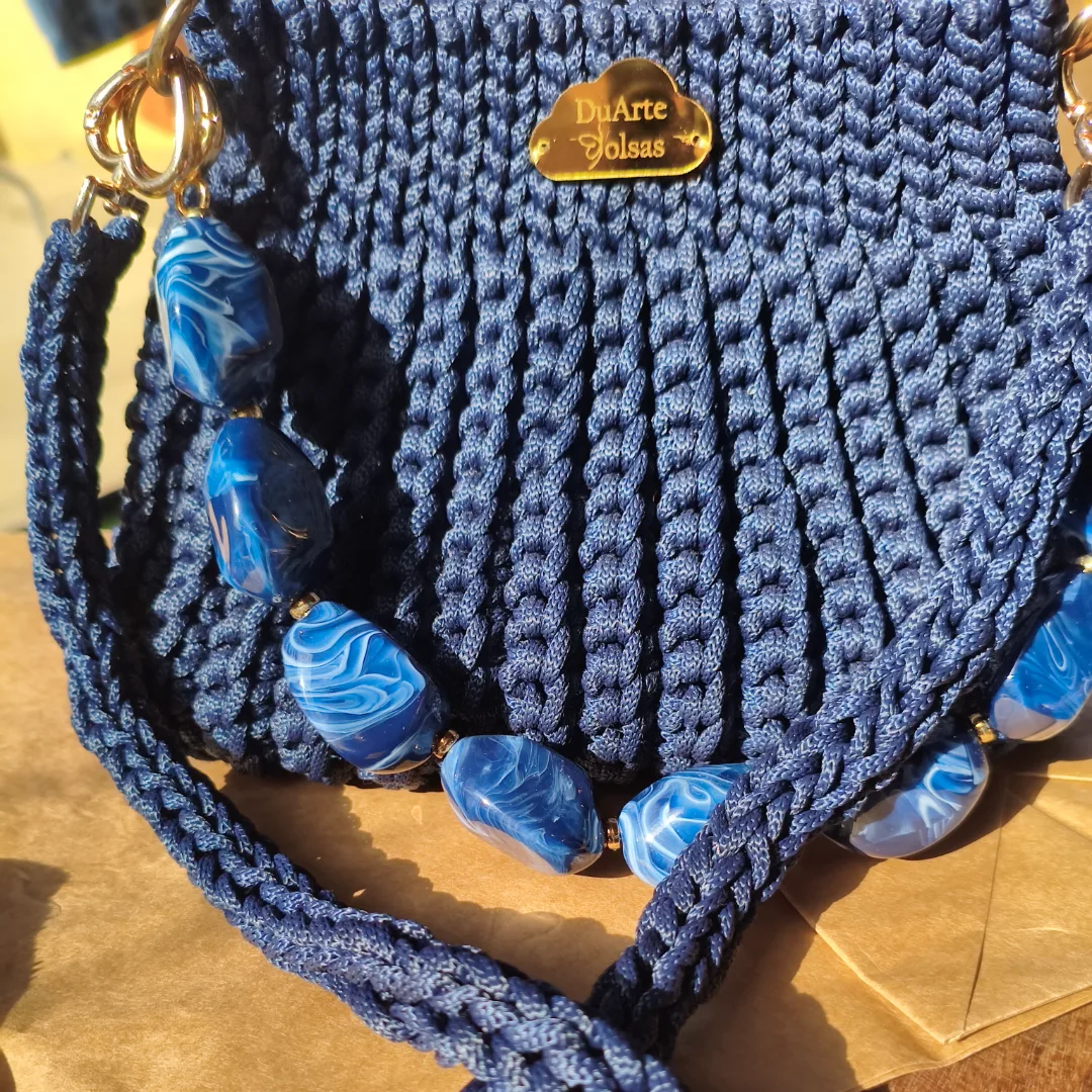 A Bolsa Pri foi criada para quem ama unir estilo, sofisticação e exclusividade em uma única peça.  Confeccionada artesanalmente em fio náutico Círculo, utilizando a combinação de pontos baixos e pontos baixo em relevo, que proporcionam uma textura elegante, firmeza e um acabamento impecável, possui um tamanho ideal para acompanhar você em passeios, eventos, encontros e ocasiões especiais, carregando seus itens essenciais com muito charme e elegância.  Um dos grandes destaques da Bolsa Pri é sua versatilidade. Ela acompanha duas opções de alças: ✨ Alça de pedraria, para um visual sofisticado e cheio de personalidade. ✨ Alça em corrente revestida com crochê, que proporciona conforto e um toque moderno.  Cada bolsa é produzida a partir de seu pedido, tornando cada peça única e especial, atendendo ao seu estilo, com o cuidado e a qualidade que somente o trabalho feito à mão pode oferecer.A Afinal, peças artesanais não seguem tendências: elas criam histórias. — foto 6